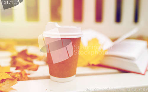 Image of coffee drink in paper cup on bench at autumn park