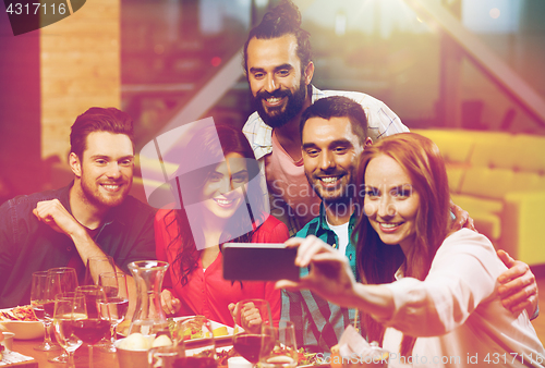 Image of friends taking selfie by smartphone at restaurant