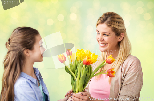 Image of happy girl giving flowers to mother over lights