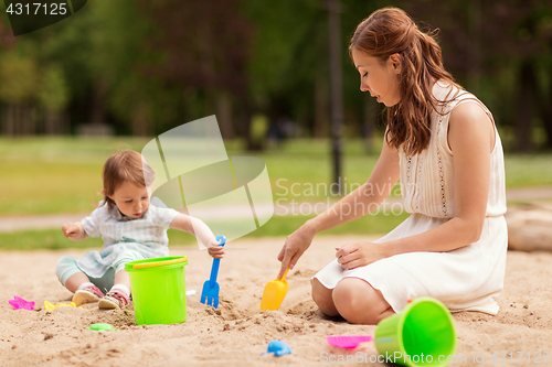 Image of happy mother and baby girl playing in sandbox