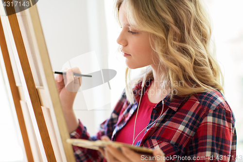 Image of student girl with easel painting at art school