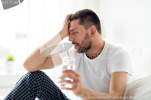 Image of man in bed with glass of water at home