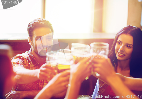 Image of happy friends drinking beer at bar or pub