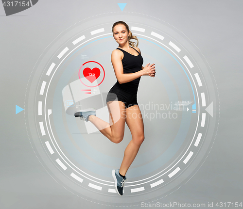Image of young woman in black sportswear jumping with pulse