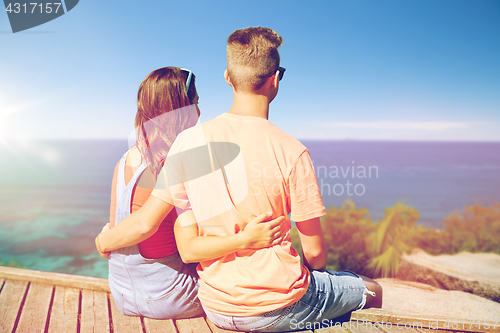 Image of happy teenage couple sitting on river berth