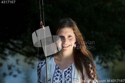 Image of Young woman with summer sprouts and dungarees while fishing