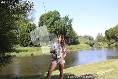 Image of Young woman with summer sprouts and dungarees while fishing