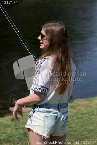 Image of Young woman with summer sprouts and dungarees while fishing
