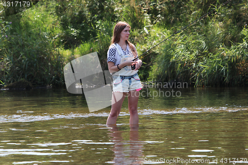 Image of Young woman with summer sprouts and dungarees while fishing