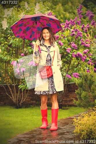 Image of European woman dressed up in a raincoat with an umbrella in the 