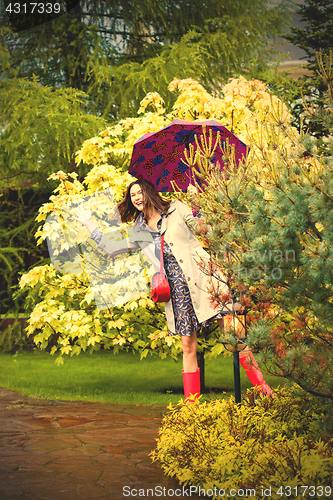 Image of funny beautiful woman with an umbrella in the rain