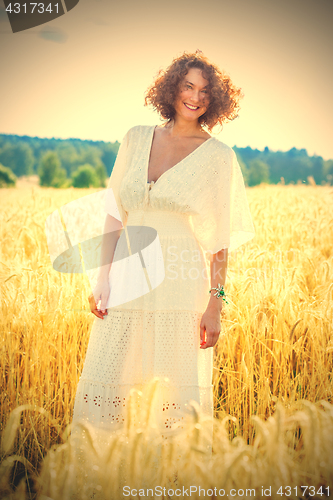Image of beautiful woman in white dress in a field outdoors on a summer d