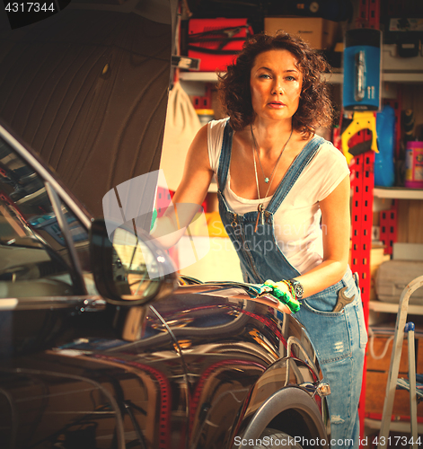 Image of woman auto mechanic in blue overalls