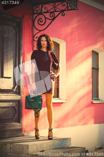 Image of beautiful woman in a burgundy dress with a green hand bag