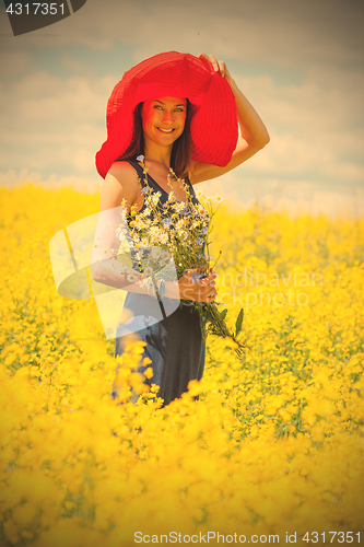 Image of beautiful white woman in a red hat and with a bouquet of wildflo