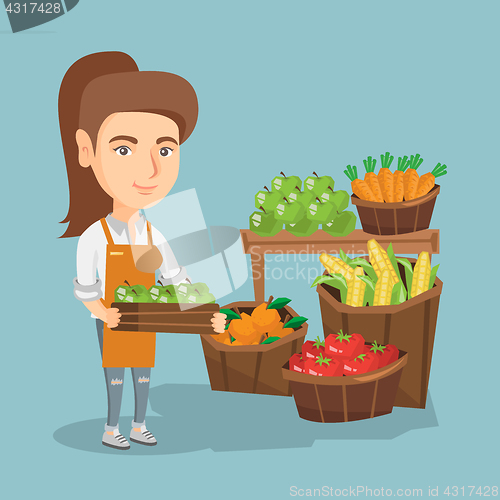 Image of Caucasian greengrocer holding box with apples.