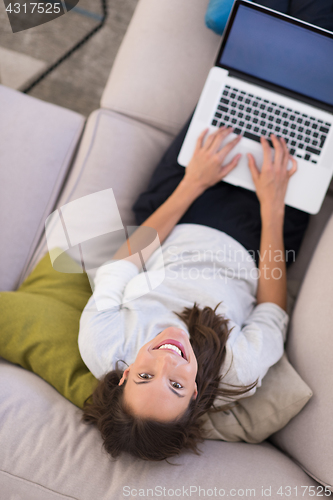 Image of Young woman using laptop at home top view