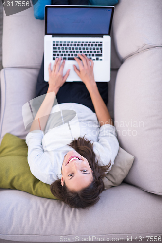 Image of Young woman using laptop at home top view