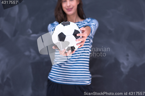 Image of woman holding a soccer ball in front of chalk drawing board