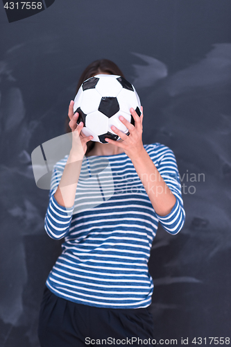 Image of woman holding a soccer ball in front of chalk drawing board