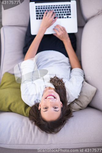 Image of Young woman using laptop at home top view