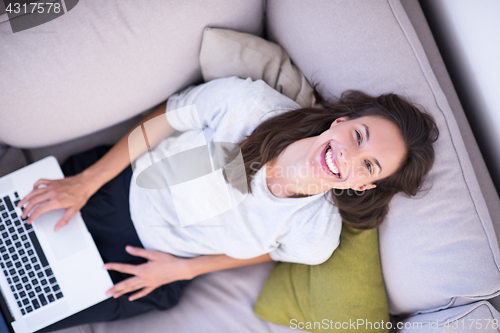 Image of Young woman using laptop at home top view
