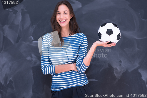 Image of woman holding a soccer ball in front of chalk drawing board