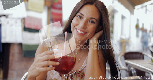 Image of Smiling woman posing with drink in cafe