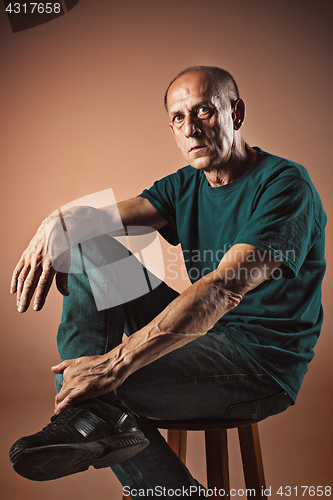 Image of Worried mature man sitting at studio