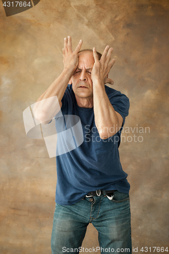 Image of Worried mature man touching his head.