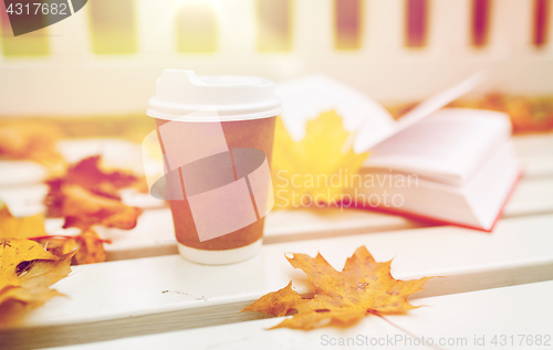 Image of coffee drink in paper cup on bench at autumn park