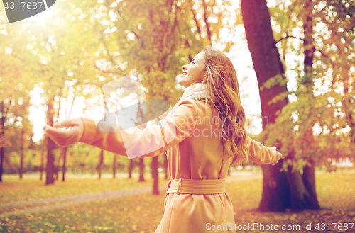 Image of beautiful happy young woman walking in autumn park