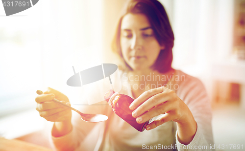 Image of woman pouring medication from bottle to spoon