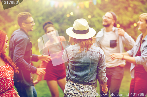 Image of happy friends dancing at summer party in garden