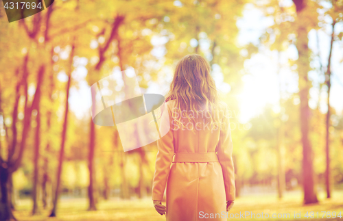 Image of beautiful young woman walking in autumn park