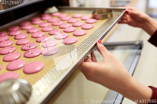 Image of chef with macarons on oven tray at confectionery