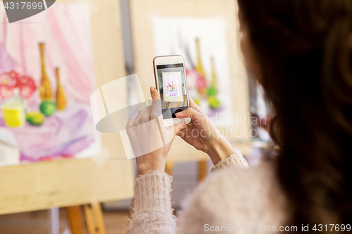 Image of woman with painting on smartphone at art school