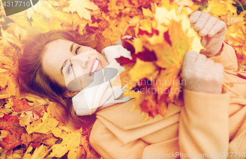 Image of beautiful happy woman lying on autumn leaves