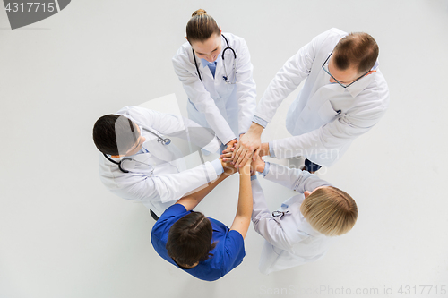 Image of group of doctors with hands together at hospital