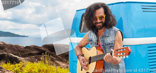 Image of hippie man playing guitar at minivan car on island