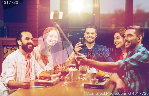 Image of friends taking selfie by smartphone at restaurant