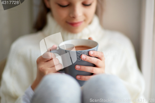 Image of girl with cacao mug looking at home window