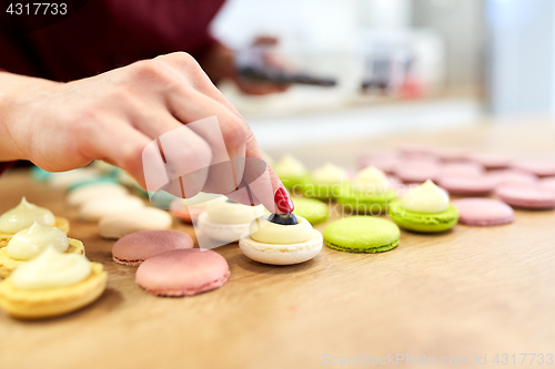 Image of chef decorating macarons shells at pastry shop