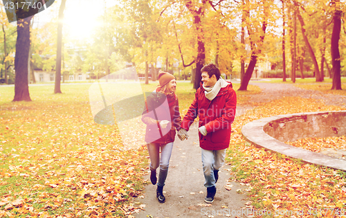 Image of happy young couple running in autumn park