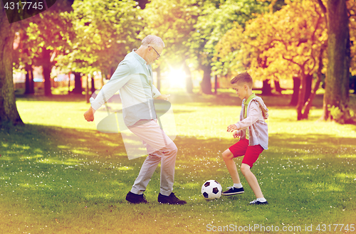 Image of old man and boy playing football at summer park