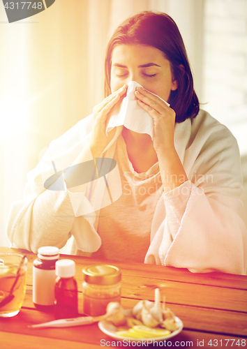 Image of sick woman with medicine blowing nose to wipe