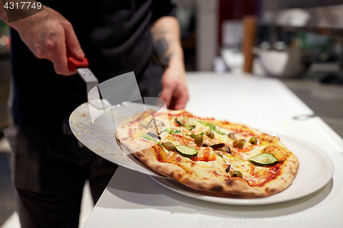 Image of cook with baked pizza on peel at pizzeria