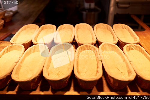 Image of yeast bread dough in baskets at bakery kitchen