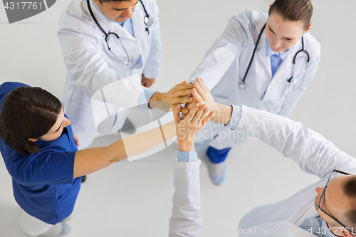 Image of group of doctors making high five at hospital