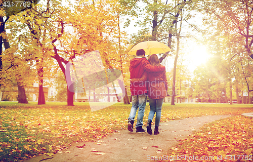 Image of happy couple with umbrella walking in autumn park